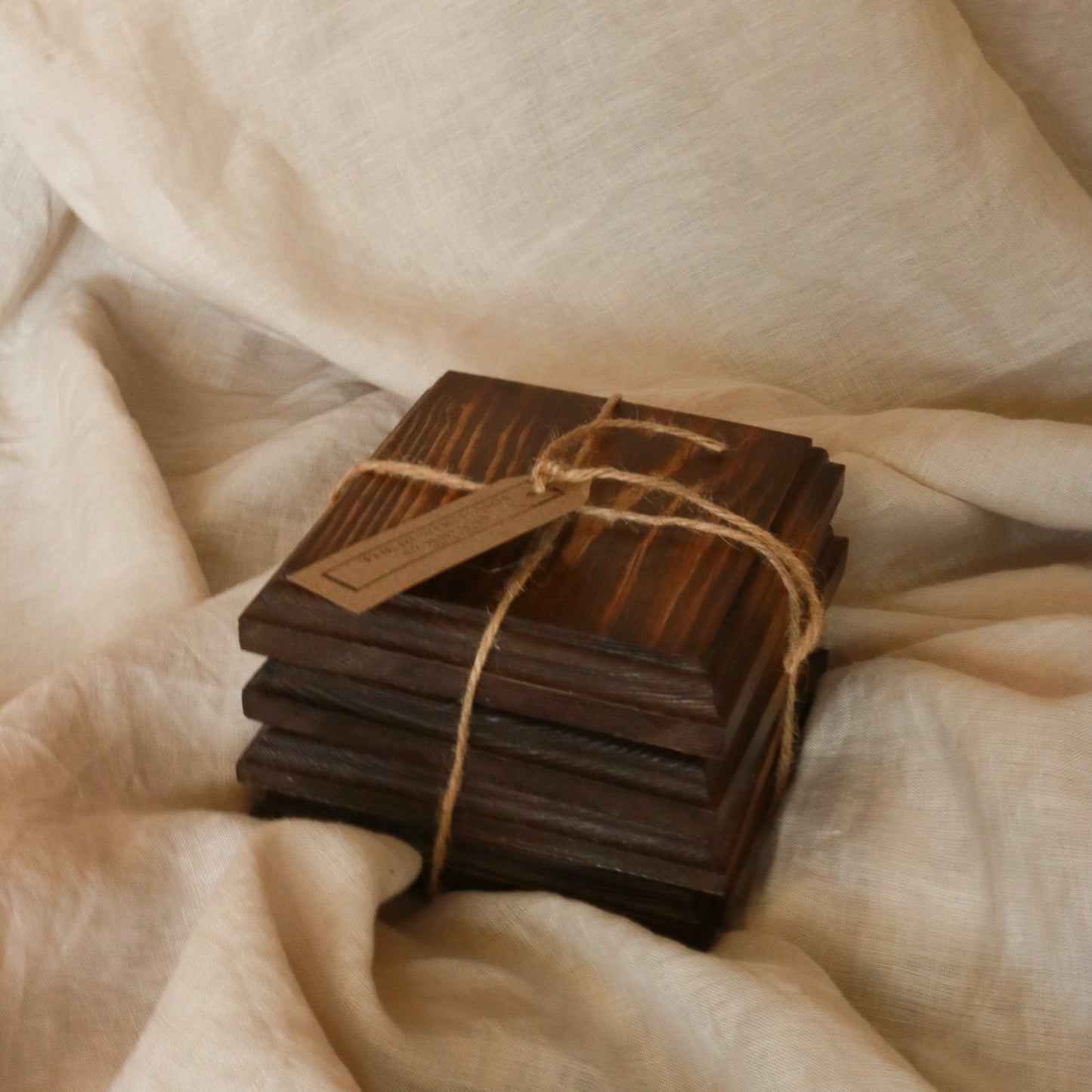 Handcrafted dark wood ribbed coasters set of 4, tied with jute twine on soft linen — rustic home accessory by The Rustic Barn Company