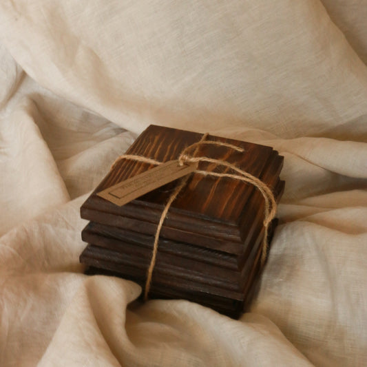 Handcrafted dark wood ribbed coasters set of 4, tied with jute twine on soft linen — rustic home accessory by The Rustic Barn Company