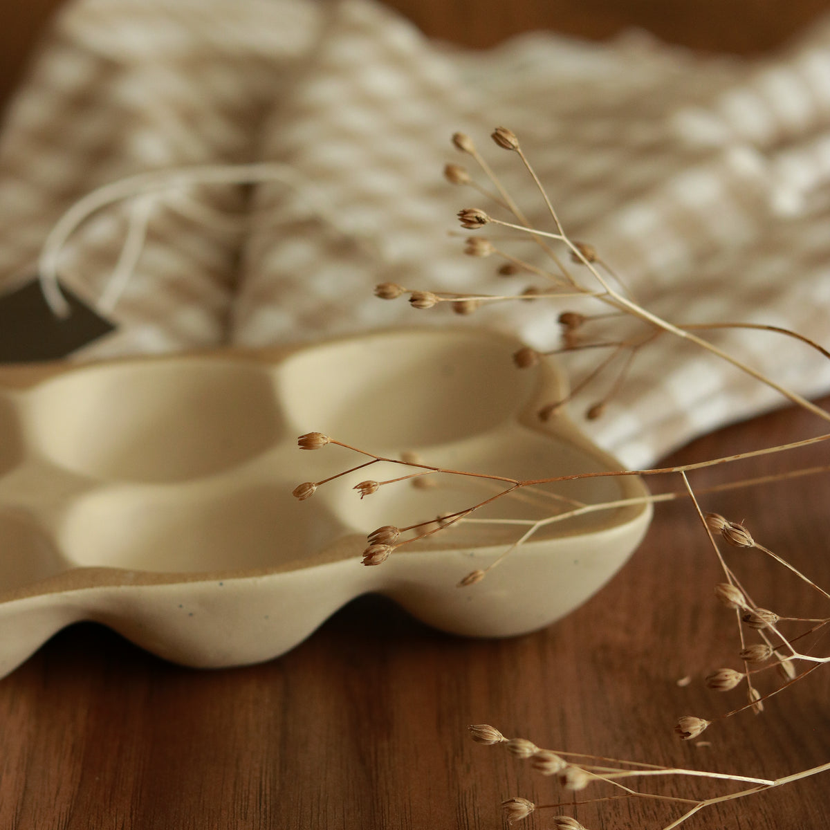 Empty Weathered Oat stoneware egg tray on a wooden table, styled with dried stems
