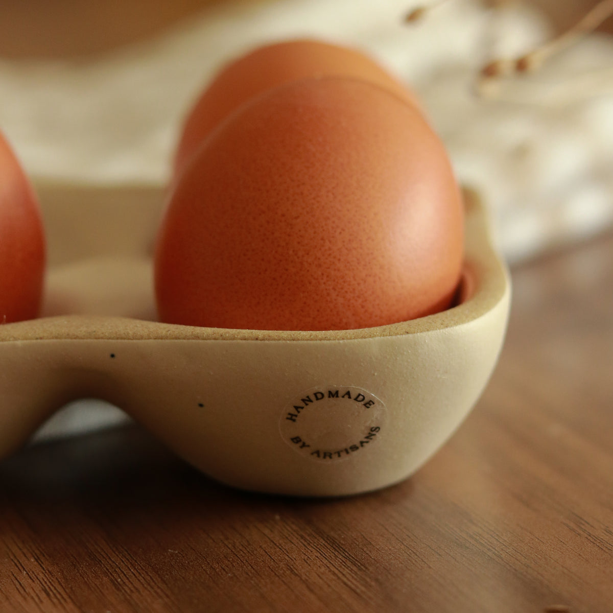 Close-up of three brown eggs in the stoneware egg tray, showing its rounded compartments