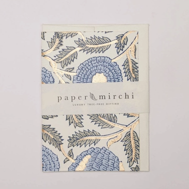 A Paper Mirchi branded gift box featuring a botanical pattern in blue, beige, and gray, wrapped with a white paper band displaying the brand name.