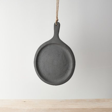 Black round mango wood serving board with handle and jute rope loop, hanging against a white background