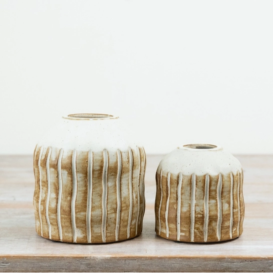 Large and small natural ribbed ceramic vases styled side by side, each with a white glazed top and ribbed brown base