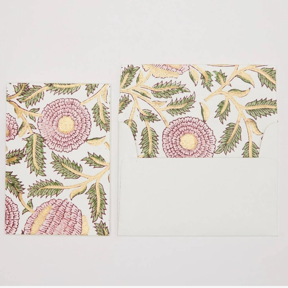 A stationery set featuring a card and matching envelope with a botanical block print pattern of pink flowers and green leaves on a white background.